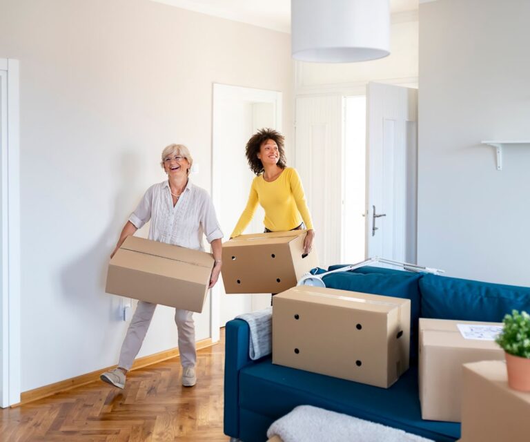 First home purchase a mum carries boxes into a new flat with her daughter