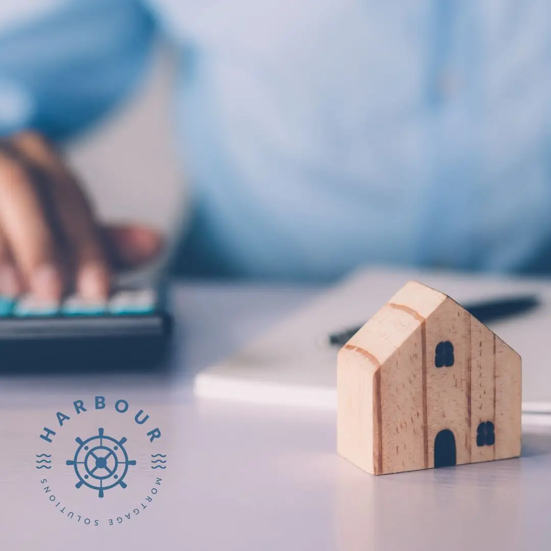 Mortgage Advisors South Wales, a wooden house on a table with a man using a calculator in background