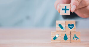Life Assurance - a hand stacking building blocks with medical symbols on them