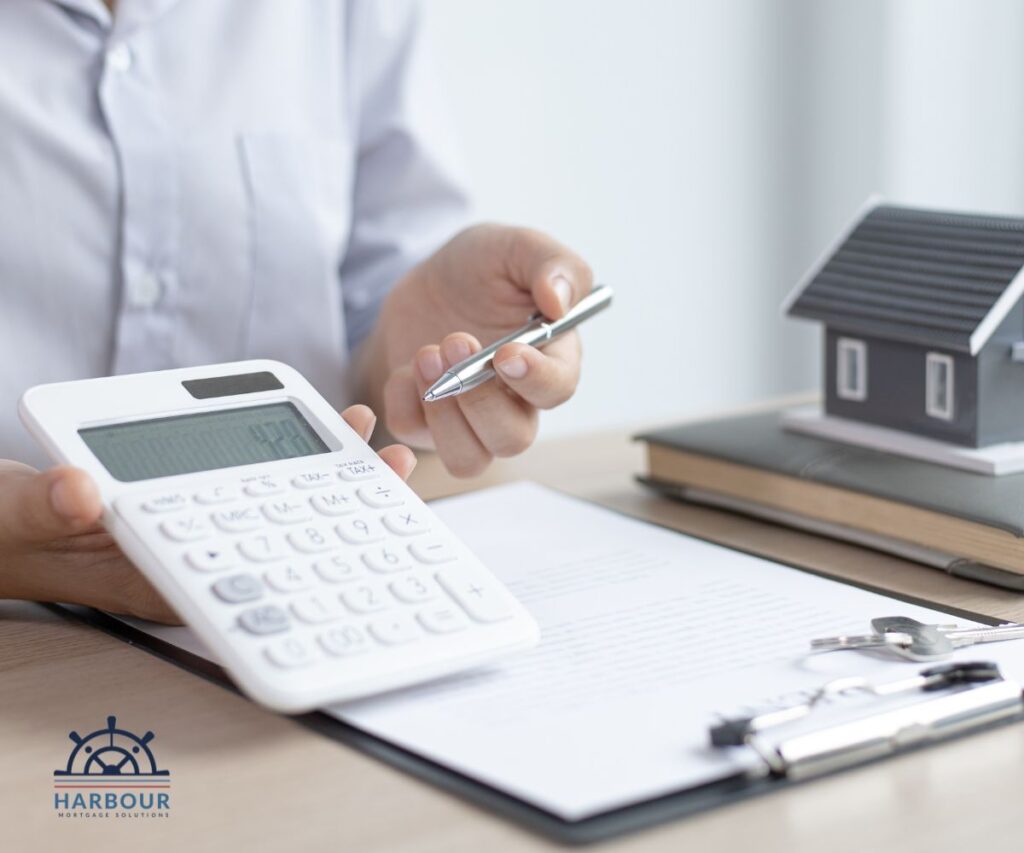 remortgage your home with an advisor like this holding a calculator out, theres a toy house, clipboard and books onhis deskthere's
