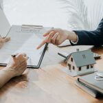 Mortgage Products someone holding a contract with a model house on their desk