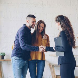 A young couple house hunting and shaking hands with an estate agent because they have a mortgage agreement in principle
